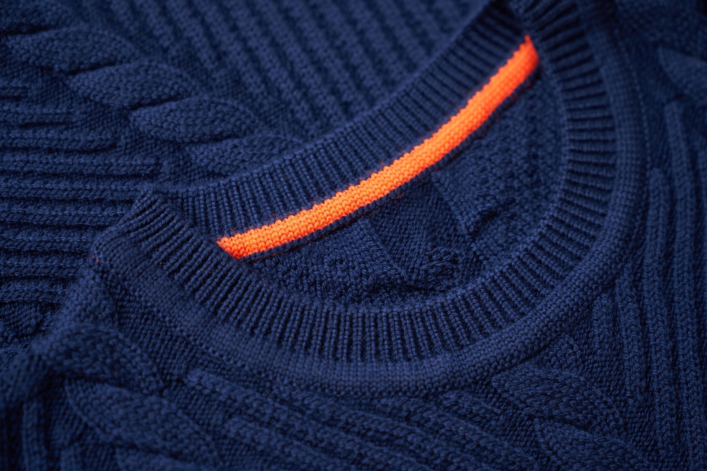 Close-up of a navy blue sweater with an orange trim